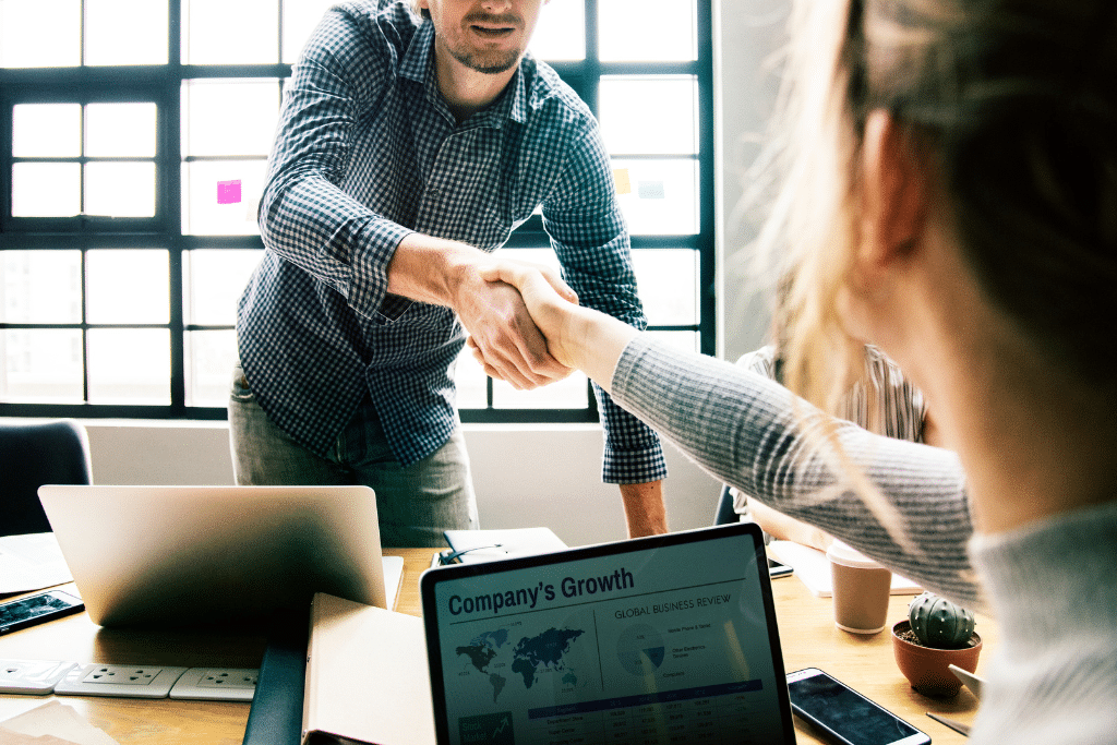 Reunión de negocios en la que dos personas estrechan la mano, simbolizando acuerdos estratégicos para mejorar la retención de clientes.