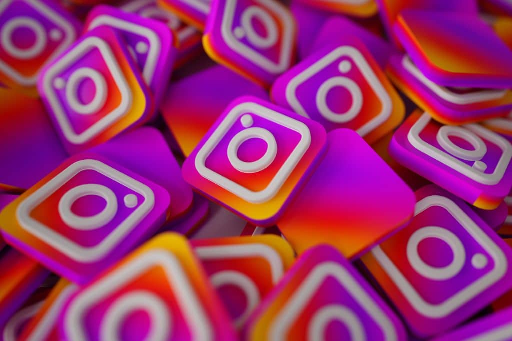 Iconos de Instagram apilados en 3D con colores degradados, ilustrando el debate sobre comprar seguidores en Instagram